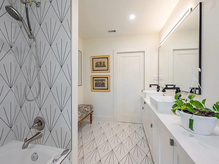 Bright bathroom with double vanity, sleek lighting, seating area, and clean contemporary finishes.