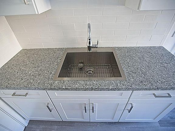 Granite countertop, stainless steel sink with deep single bowl, pull out sprayer faucet, brand new shaker cabinets.