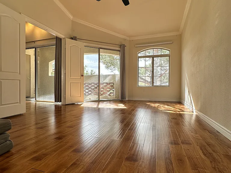 Spacious master bedroom with high ceilings, filled with natural light, and featuring a ceiling fan.