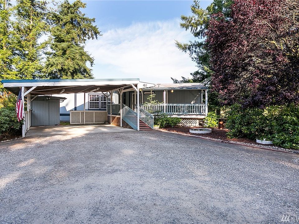 Front exterior with mature landscaping, double carport, storage unit, and guest parking