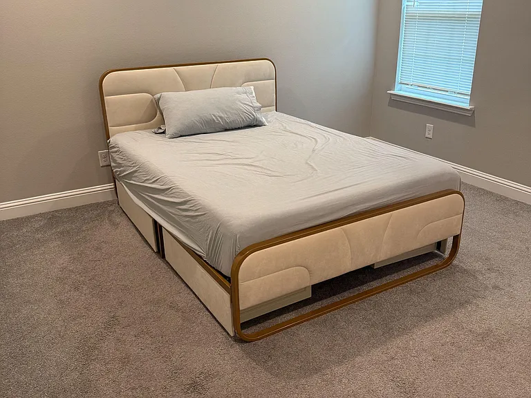 Carpeted bedroom with a comfortable bed, neutral walls, and a window with blinds for privacy and natural light.