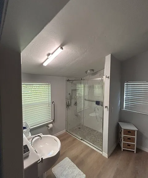 Bathroom has walk-in shower, pedestal sink, a mini split and a barn door and instant on water heater