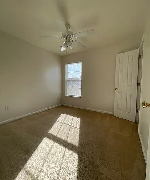Second bedroom filters in natural light, has a ceiling fan and closet.