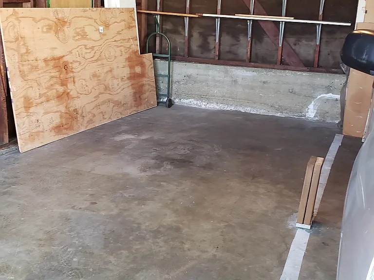 Left side of interior of garage, highlighting parking space within detached garage.