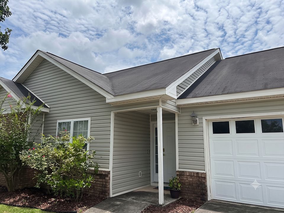 Charming front entryway featuring a quiet covered porch and attached garage parking.