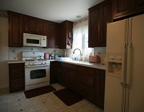 The kitchen has beautiful cherry cabinets, stove, microwave