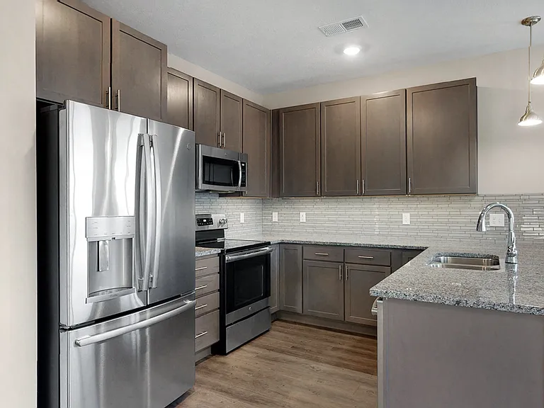 This 2 bedroom Marigold with den floor plan at WH Flats features a tile backsplash (available in some homes), stainless steel appliances, granite countertops and large peninsula.