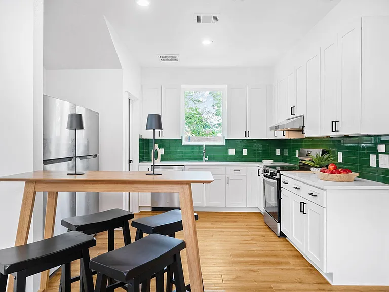 Updated kitchen with ample shaker cabinetry, stainless appliances, and a peninsula with seating beside a windowed sink.
