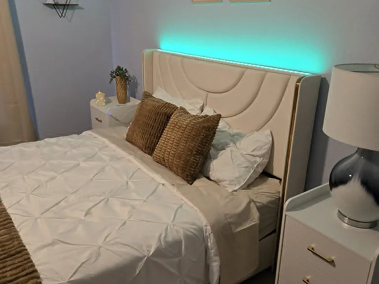 Private bedroom featuring a brand-new queen-size bed with a built-in headboard and adjustable lighting. Includes matching three-drawer nightstands on each side for convenient storage, creating a comfortable, stylish, and move-in-ready space.
