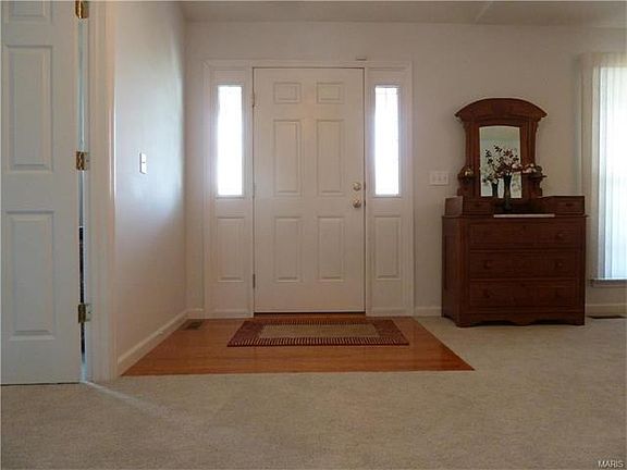Spacious entry foyer with a vaulted ceiling. The decor is neutral and is accented with white 6 panel doors.