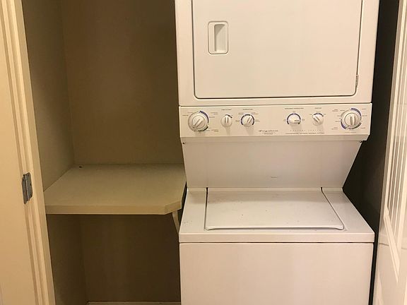 Stacked washer and dryer with hanging space behind doors off kitchen