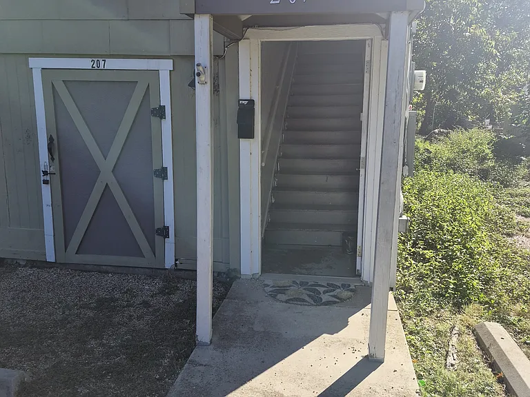 Front porch and door to stairs. Storage unit to the left.