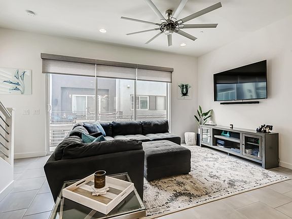 Living room with 55" TV and motorized Lutron shades. Slider opens to a balcony