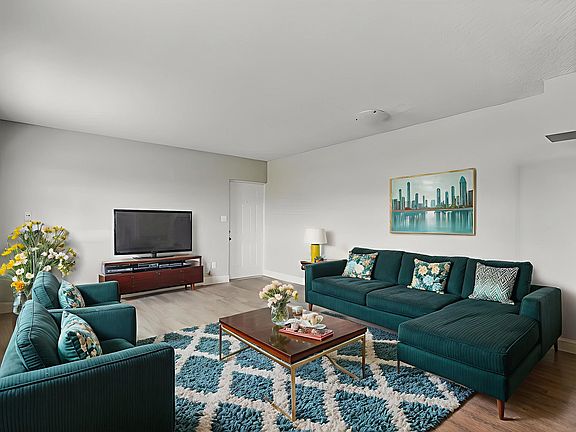 Inviting living room with plush teal sofas, stylish decor, and natural light for a cozy ambiance.