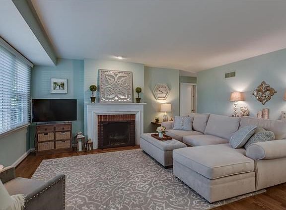 Spacious living room opens to dining room featuring beautiful large window, gas log fireplace and wood floors