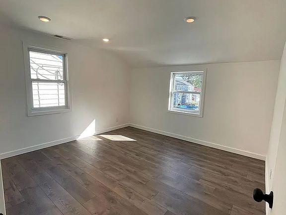 Large, sun-filled bedroom with new flooring, LED recessed lighting, and double windows.