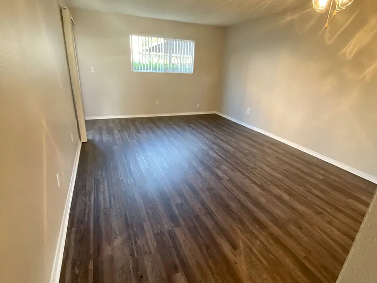 Plank style flooring in living room and dining area with ceiling fan at Villa Pacific Apartments in Oceanside, California.