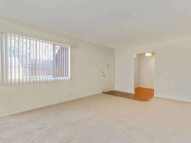 Living room with carpet flooring, vertical blinds on the windows