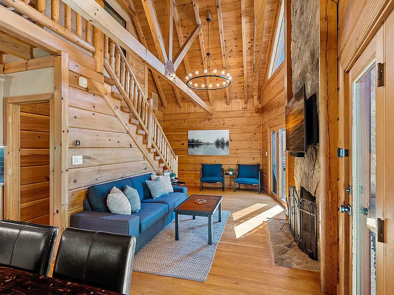 2 story family room with lake views. Pine clad walls and ceiling, wooden ceiling beams and modern wagon wheel chandeliers.