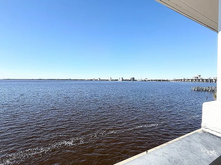 Breathtaking waterfront view from balcony, showcasing expansive blue waters and clear skies, perfect for relaxation.