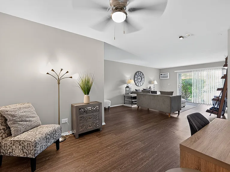 Relax in a bright living room featuring a cozy chair and fresh greenery at Renaissance at Carol Stream in Carol Stream, IL.