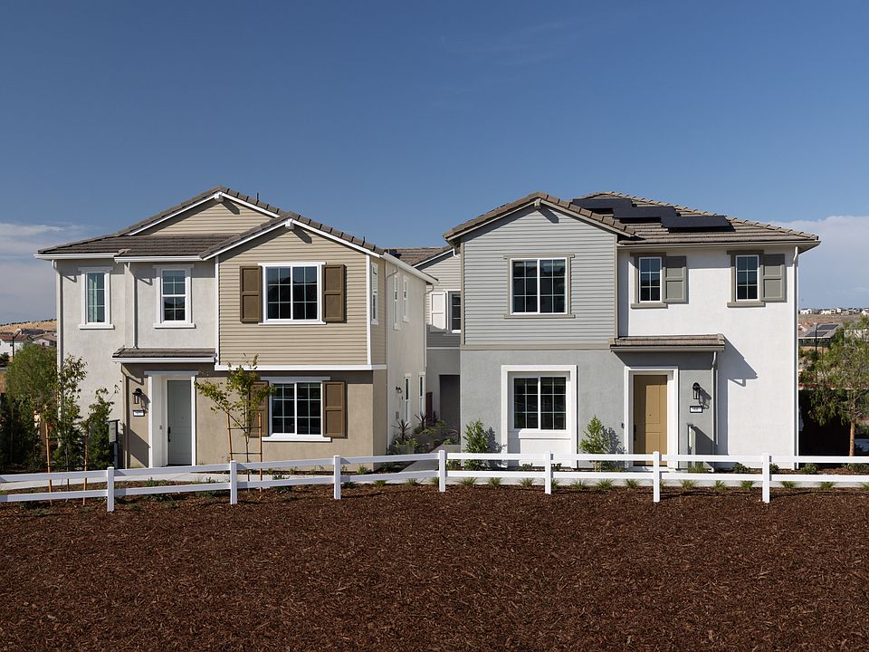 The image shows a pair of two-story residential houses with gray siding and white trim, surrounded b
