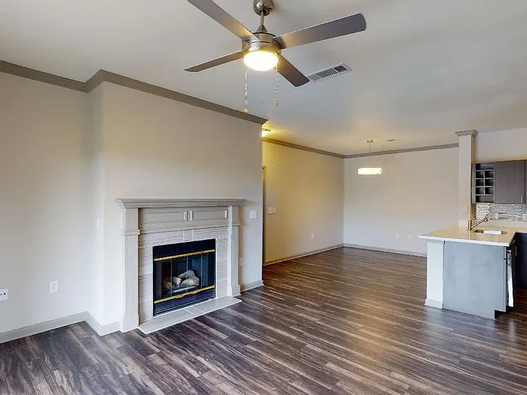 Apartment dining and living room with wood-style flooring and fireplace in select homes.