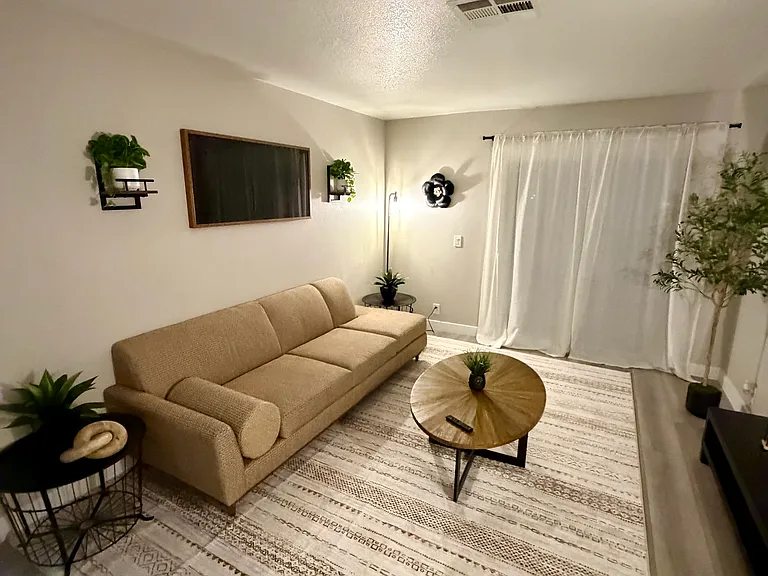 Bright and inviting fully furnished living room featuring modern decor, comfortable seating, and direct access to a private patio, designed for relaxing and everyday comfort.
