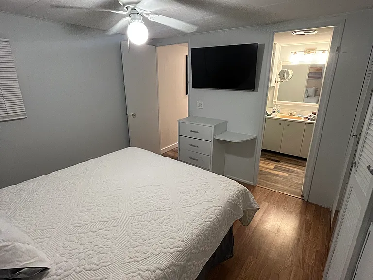 The primary bedroom has a wall mounted TV and the entrance to a private bath to the right.