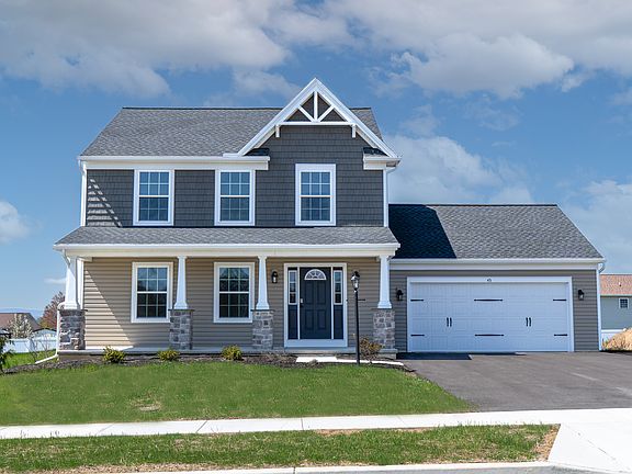 Full front-facing image of a two-story home featuring a covered front porch, stone columns, and a bl