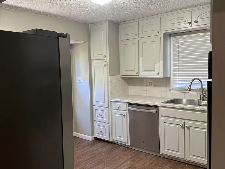 Efficient kitchen with ample white cabinetry, stainless dishwasher, and a window over the sink for everyday convenience.
