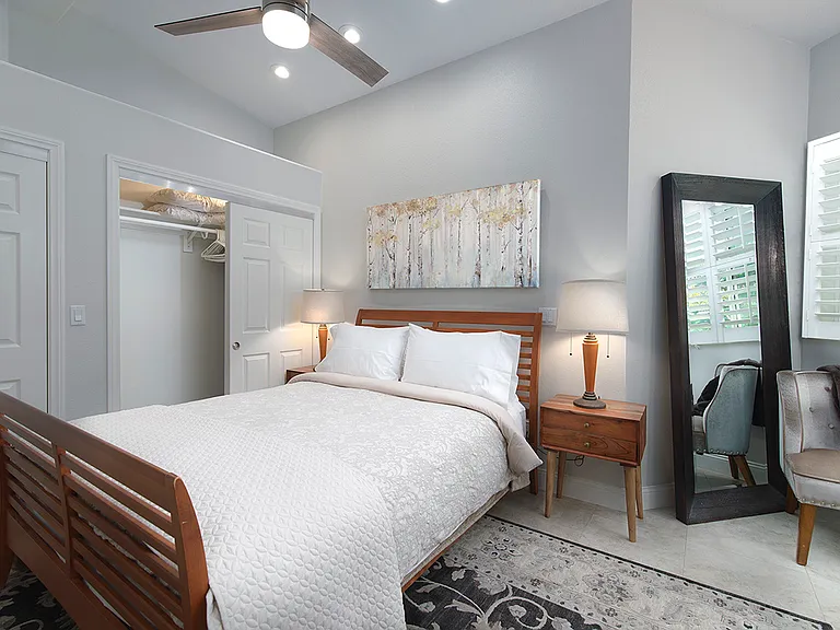 Primary bedroom has to nightstands with individual table lamps and a ceiling fan directly above the bed.