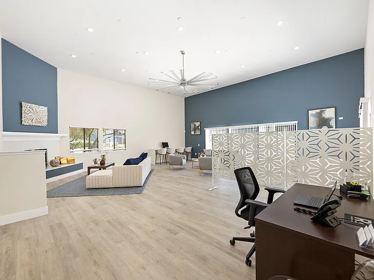 Bright and spacious open-concept living area with modern decor, featuring elegant blue accent wall, cozy seating, and stylish partition for workspace.