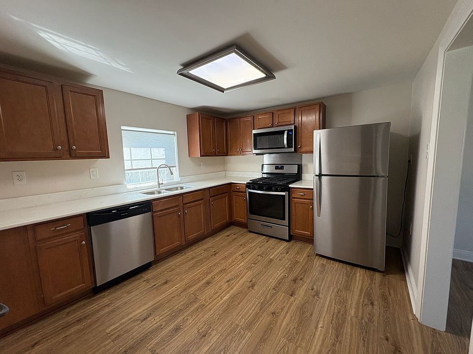 Separate kitchen with stainless appliances, including dishwasher, refrigerator with ice maker, quartz countertops.