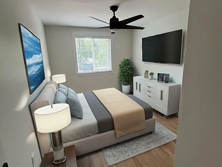 Inviting bedroom with modern ceiling fan, sleek furniture, and ample natural light.