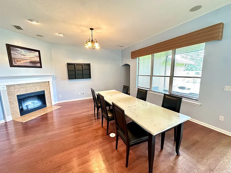 Dedicated dining area with a large window, hardwood floors, and an adjoining fireplaceideal for everyday meals or hosting.