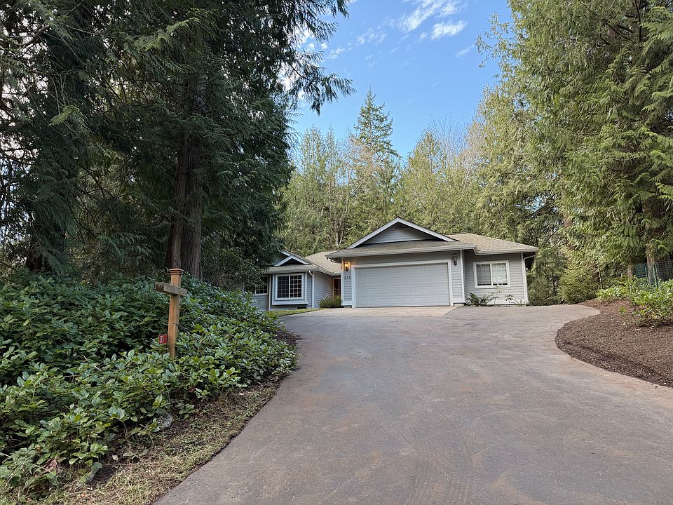 Three bedroom, two bathroom house as seen from the street, with two-car garage and additional workshop or storage area. Two separate decks and a large fenced-in area are behind the house.