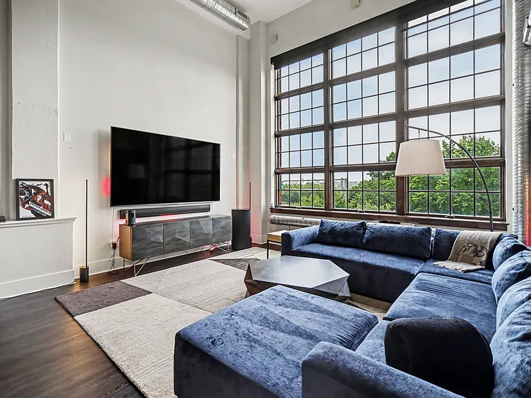 Floor to ceiling windows flood the living room with natural light. Massive 100" TV with theater sound system and immersive lights