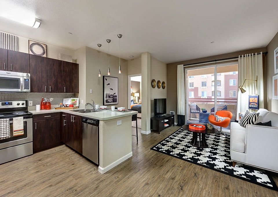 Staged living room and kitchen with breakfast bar and stainless steel appliances. Hardwood-style vinyl flooring throughout