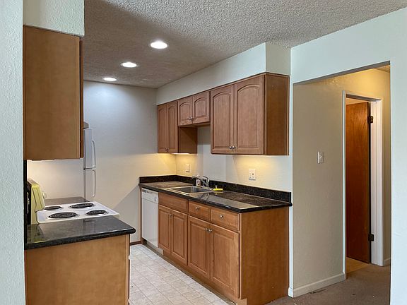 Galley style kitchen (View 2) with all electric appliances, granite countertops, undercabinet lighting, and soft close cabinetry.