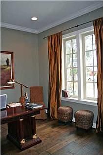 Casually elegant silk draperies accent the graceful windows in the living room/study.