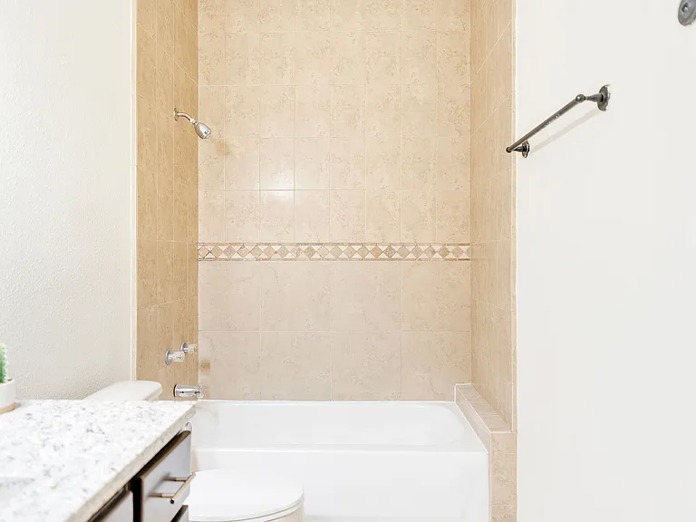 Interior view of a bathroom in Merida Vista Apartments, Laredo, Texas, showcasing a tub, toilet, and sink