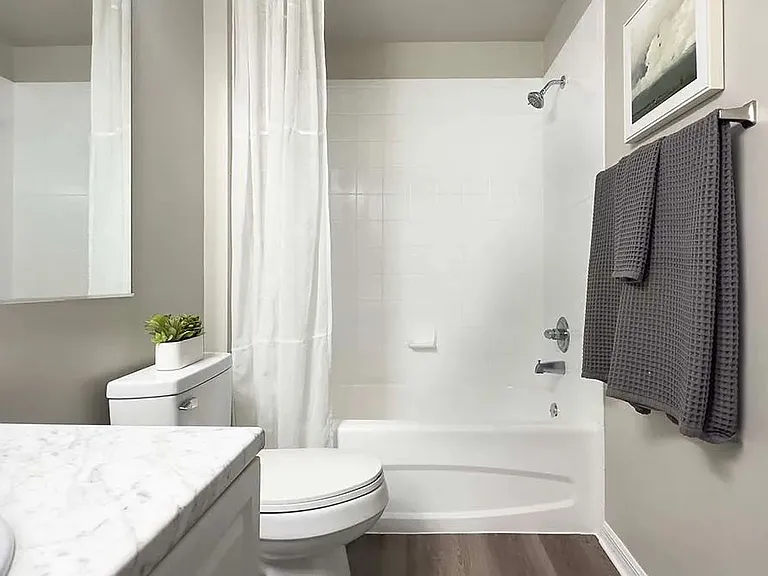 Guest bathrooms offer luxurious space with large mirrors, wood-style flooring, and a cozy shower/tub combo.