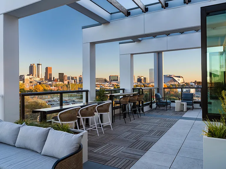 Rooftop seating framed by skyline views, with shaded lounge areas and bar-height tables designed for casual gatherings and quiet moments outdoors.