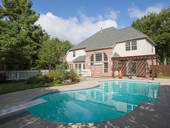 Private backyard boasts privacy fence, extended cool decking and charming white picket fence that enhances security around the pool area.