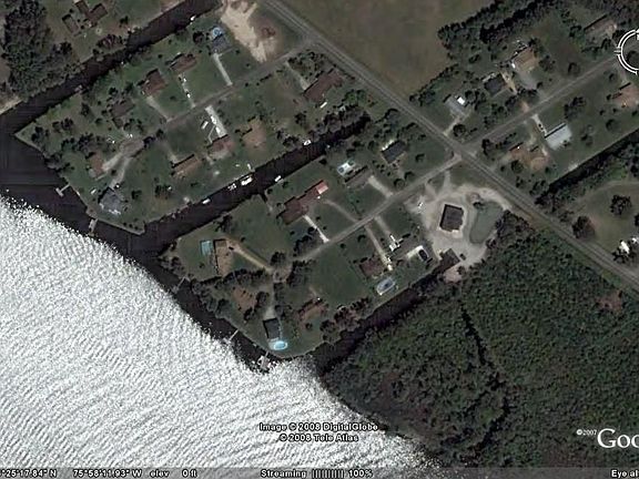 Red structure in the middle with a boat parked in the water behind the house