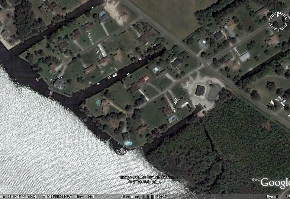 Red structure in the middle with a boat parked in the water behind the house