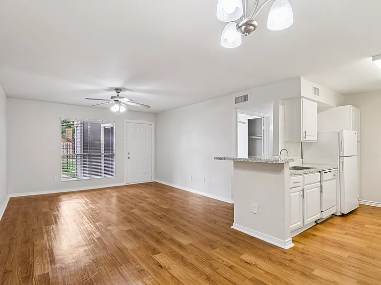 Charming open-concept living space with bright lighting, wood-style floors, and a modern kitchen featuring sleek countertops and white cabinetry. Charming open-concept living space with bright lighting, wood-style floors, and a modern kitchen featuring sl