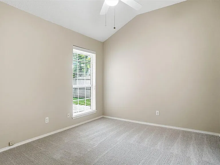 Room with a vaulted ceiling and a ceiling fan
