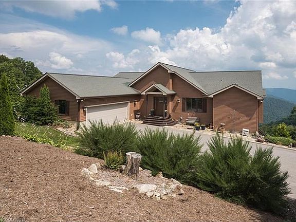 Back of the house with paved driveway and oversized 2 car garage. Beautiful landscaping.